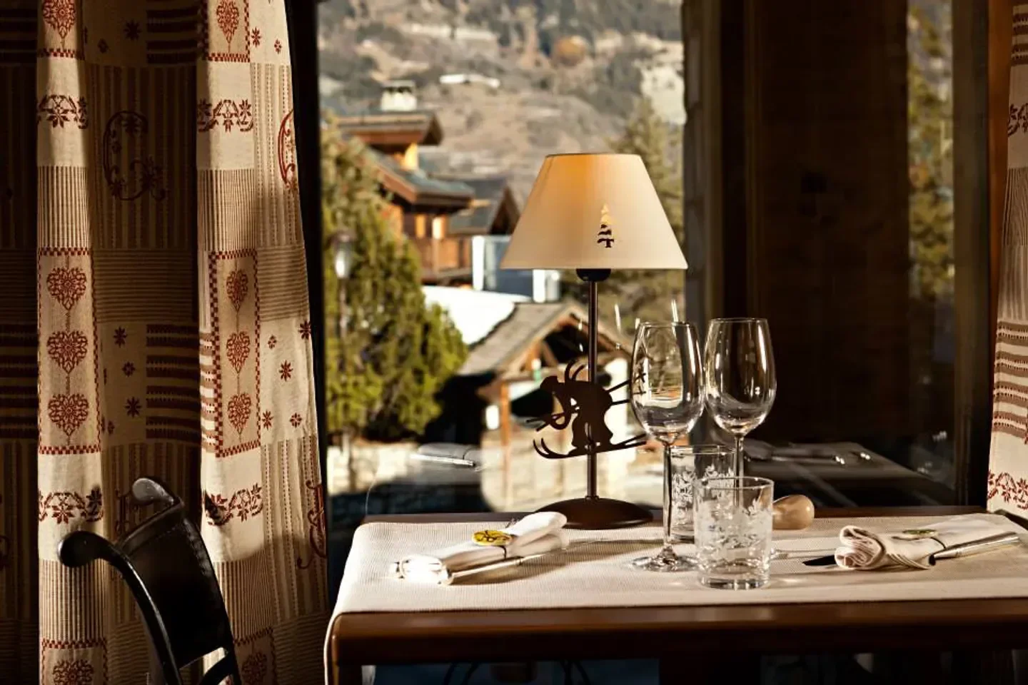 Cozy table setting at Azimut restaurant in Courchevel, with mountain views and decorative lamp.