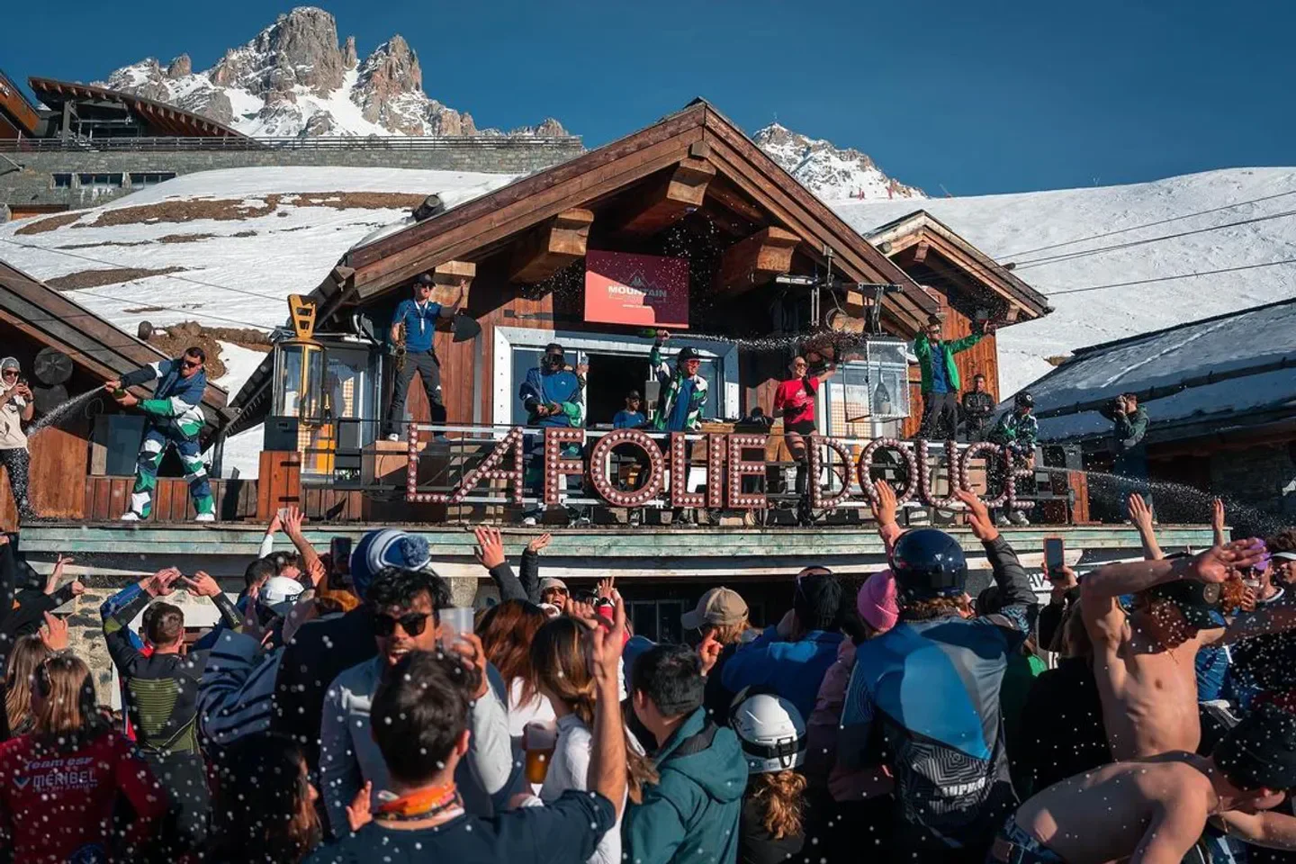 Party scene at La Folie Douce in Courchevel with snow-capped mountains in the background.
