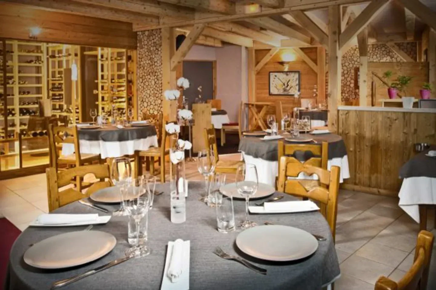 Cozy dining room at Le Farçon restaurant in Courchevel with wooden beams and elegant tables.