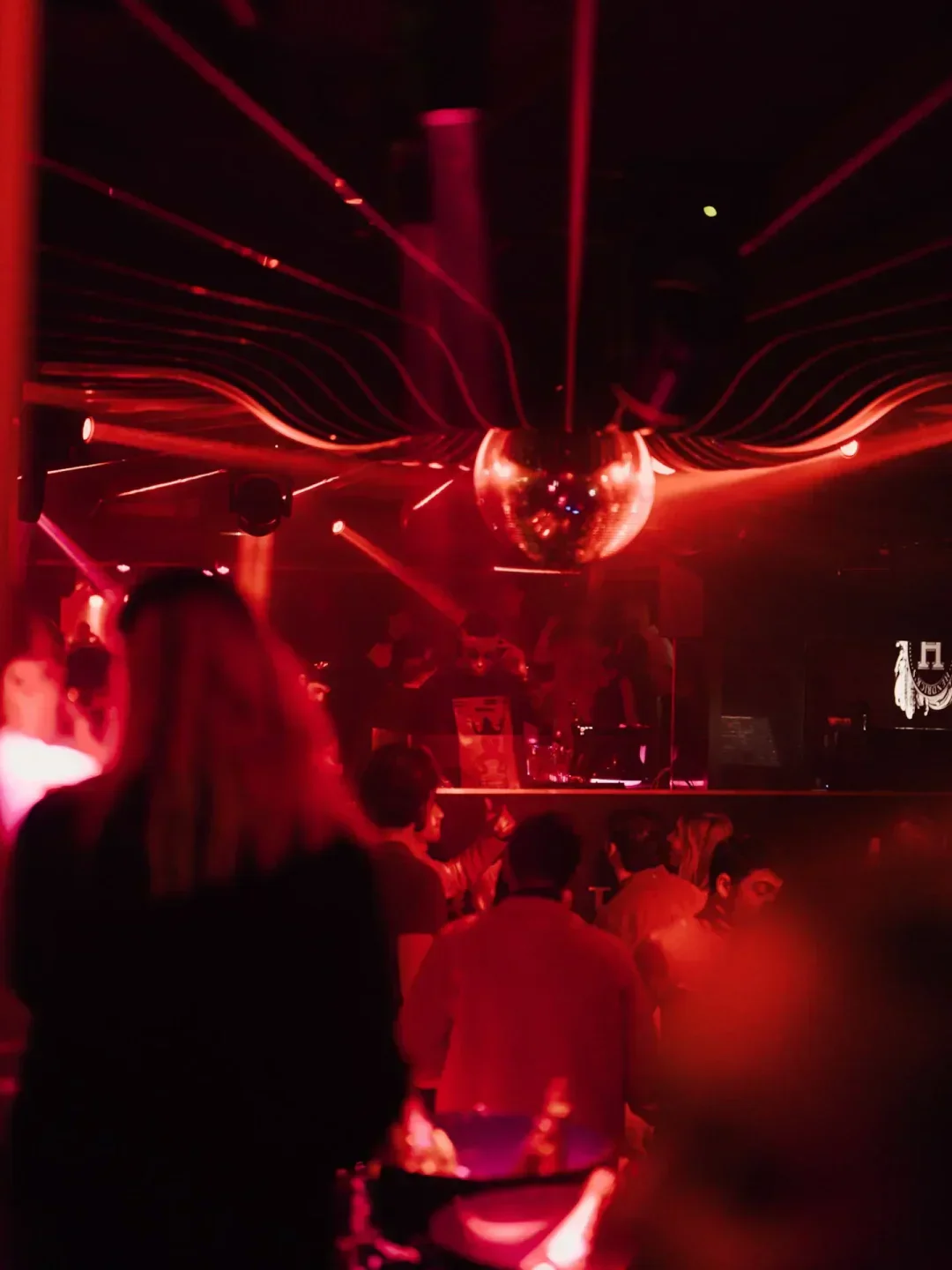 Inside Les Caves de Courchevel nightclub in Courchevel with a disco ball and red lights.